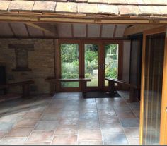 an empty room with stone floors and wooden doors leading to a patio area that has a bench on the other side