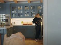 a woman is standing in the kitchen looking into the dining room and living room area