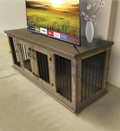 a flat screen tv sitting on top of a wooden entertainment center next to a vase with flowers