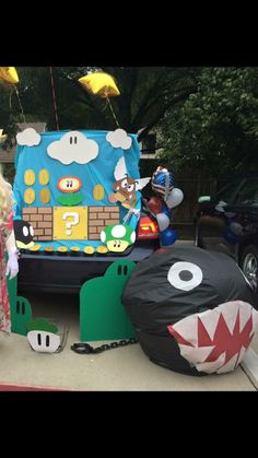 a woman standing in front of a car decorated with mario and luigi's house