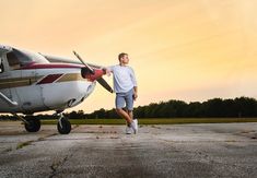 a man standing next to an airplane on top of a tarmac at sunset or dawn