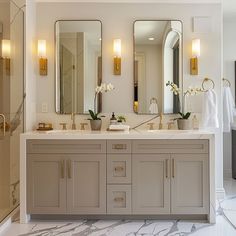 a bathroom with two sinks, mirrors and lights on the wall above them is shown