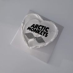 a white heart shaped cake with the words arctic monkeys on it's frosting