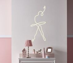 a white fireplace with a neon light drawing on the wall above it and a pink lamp next to it