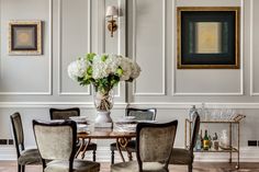 a dining room table with chairs and a vase filled with flowers on top of it