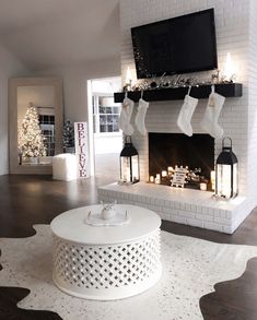 a living room decorated for christmas with stockings hanging over the fireplace and candles on the mantle