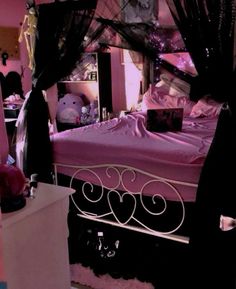 a bedroom with a pink bed and black drapes on the canopy over it's headboard