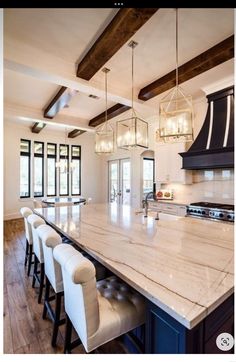 a large kitchen with marble counter tops and white chairs