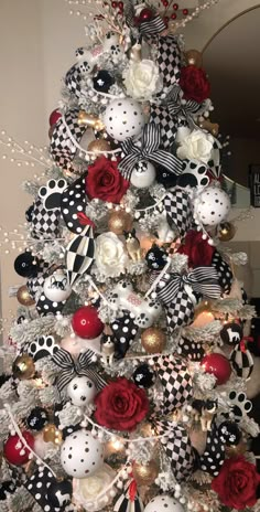 a christmas tree decorated with black and white ornaments, red roses, and bowknots