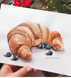 a drawing of a croissant with blueberries on it's side, in front of a christmas tree