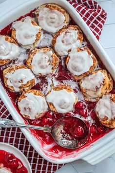 a white dish filled with pastries covered in icing and cranberry sauce