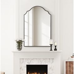 a white fireplace with a mirror above it and candles on the mantle next to it