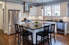 a kitchen with white cabinets and black chairs