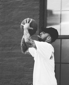 a man holding a basketball in front of a brick building while standing next to a window