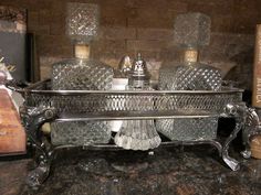 an ornate silver tray with three glass bottles on it and some books in the background