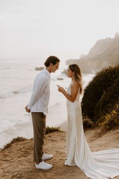 a bride and groom kissing on the beach