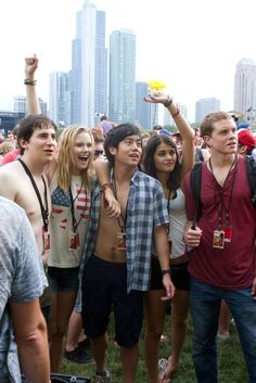 a group of young people standing next to each other on top of a grass covered field