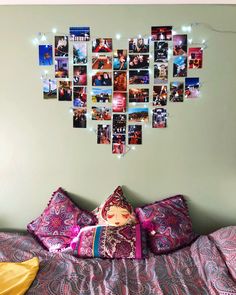 a bed topped with lots of pillows and pictures on the wall above it's headboard