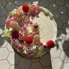 a white cake with raspberries and flowers on it