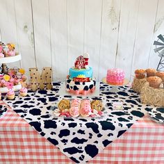 a table topped with cakes and cupcakes on top of a checkered table cloth