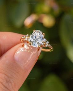 a woman's hand holding an engagement ring with two diamonds on it and the top half