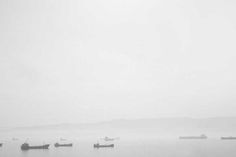 several boats floating in the water on a foggy day