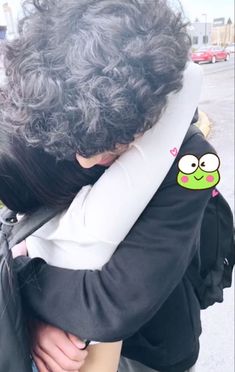 a person with curly hair hugging another persons shoulder