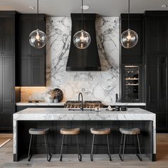 a kitchen with black cabinets and marble counter tops, hanging lights above the island area