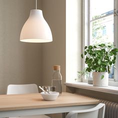 a dining room table with white chairs and a light hanging over it