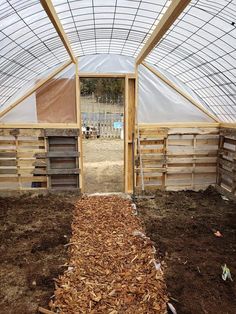 the inside of a greenhouse with wooden pallets and plastic coverings on the walls