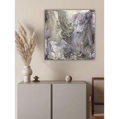 an abstract painting hangs on the wall above a cabinet