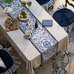 the table is set with blue and white cloths on it, along with bowls of fruit