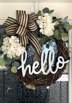 a wreath with the word hello painted on it and some flowers hanging from the front door