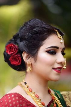 a woman wearing a red and green sari with flowers in her hair is smiling at the camera