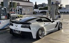 a white sports car parked at a gas station