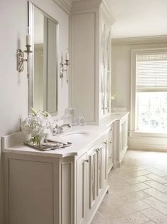 a white bathroom with double sinks and large mirrors on the wall next to each other