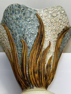 a ceramic vase with an abstract design on the top and bottom, sitting on a white surface