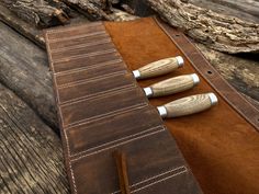 three wooden knives sitting on top of a brown leather case