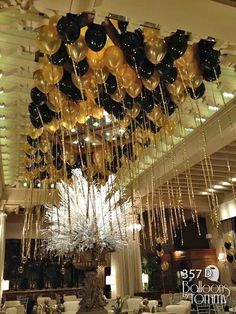 black and gold balloons are hanging from the ceiling in this elegant dining room with chandelier