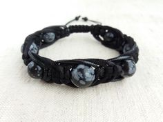 "The protection bracelet made of beads Snowflake obsidian (12mm, 10mm) , braided with three cords of different texture (satin cord, waxed cord and leather cord). Obsidian is lustrous volcanic glass; molten lava that cooled so quickly it had no time to crystallize. Obsidian has no boundaries or limitations, as a result works extremely fast and with great power. Obsidian is a strongly protective stone, forming a shield against negativity, provides a grounding cord from the base chakra to the cente Hand Wrapped Black Jewelry With Waxed Cord, Adjustable Black Braided Beaded Bracelets, Handmade Black Spiritual Leather Bracelet, Bohemian Black Leather Bracelet With Round Beads, Black Bohemian Leather Bracelet With Round Beads, Handmade Black Leather Braided Bracelet, Casual Black Hand Wrapped Braided Bracelets, Casual Black Hand Wrapped Braided Bracelet, Adjustable Black Leather Bracelet With Round Beads