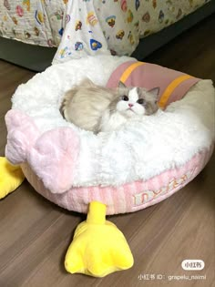 a gray and white cat laying on top of a bed next to a stuffed duck