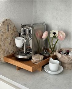 a coffee maker sitting on top of a counter next to some cups and saucers