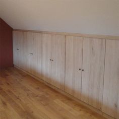 an empty room with wooden cabinets and hard wood flooring