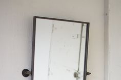 a bathroom mirror sitting on top of a white wall