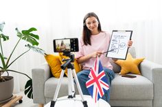 a woman sitting on a couch holding up a clipboard with the flag of great britain