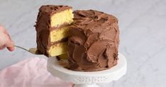 a person is holding a fork and cutting into a cake with chocolate frosting on it