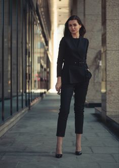 a woman in black is standing on the sidewalk