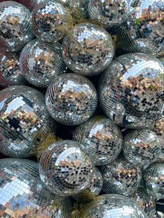 many shiny disco balls are stacked on top of each other in a pile with grass