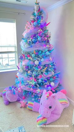 a very colorful christmas tree with an elephant stuffed animal in the middle and other decorations around it