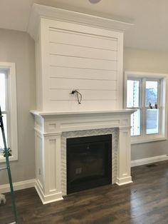 an empty living room with a fireplace and hard wood floors